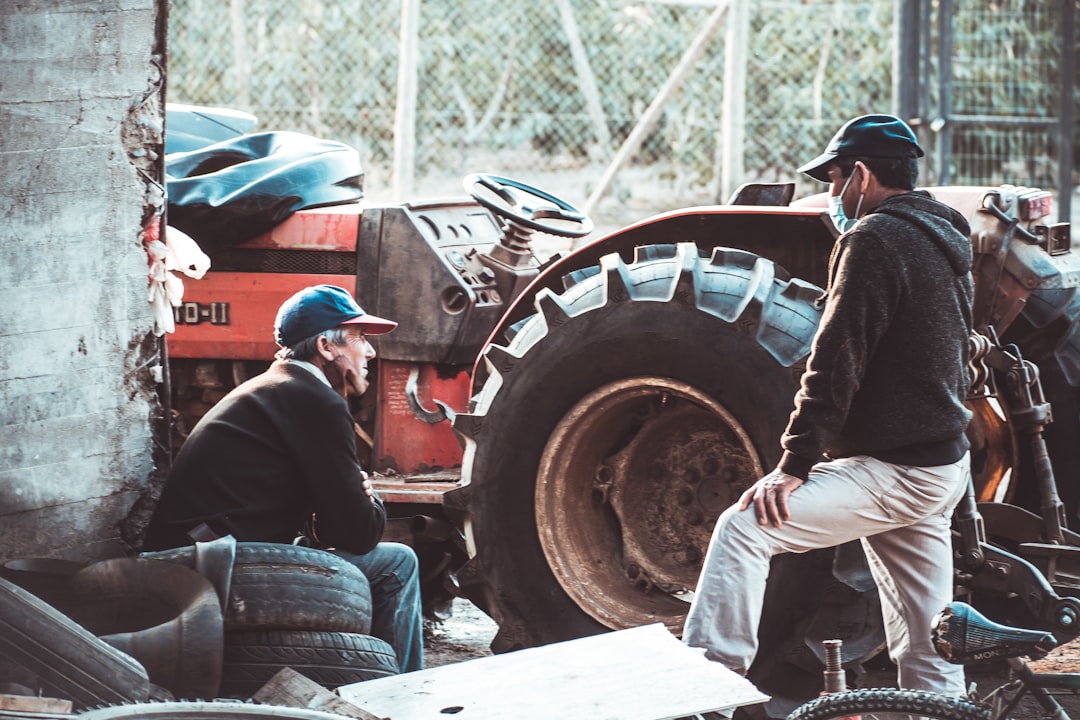 Un agriculteur en salopette est penché sur le moteur ouvert d