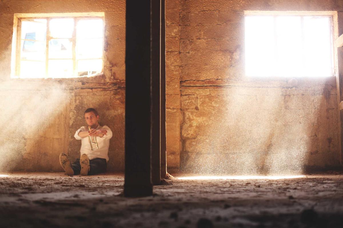 A person sitting in a dimly lit, dilapidated room.