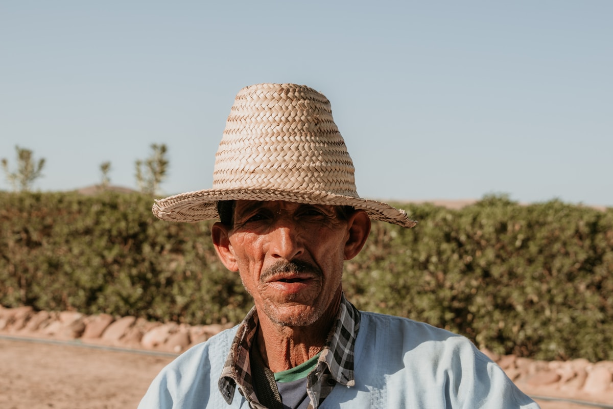 A man wears a straw hat and looks at the camera.