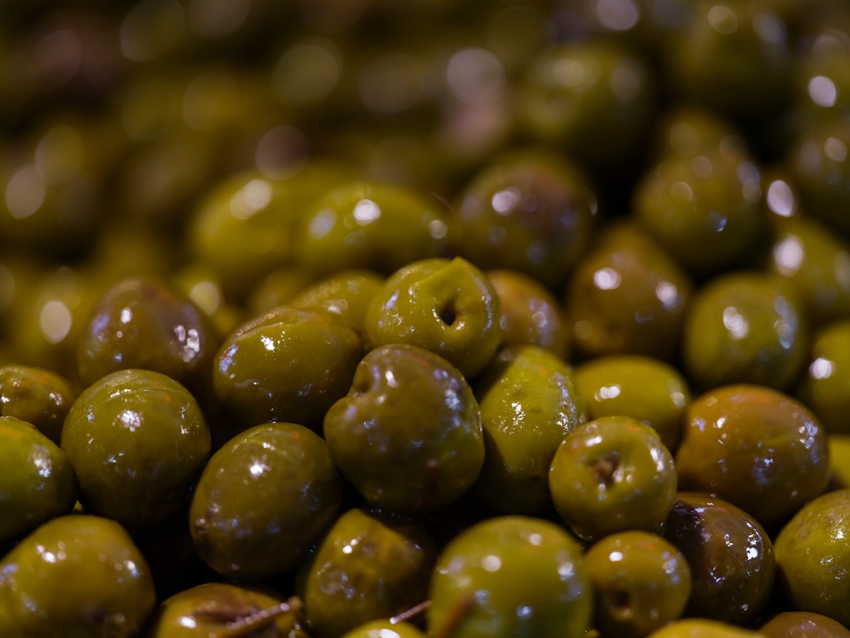 Pile of glossy green olives with pits