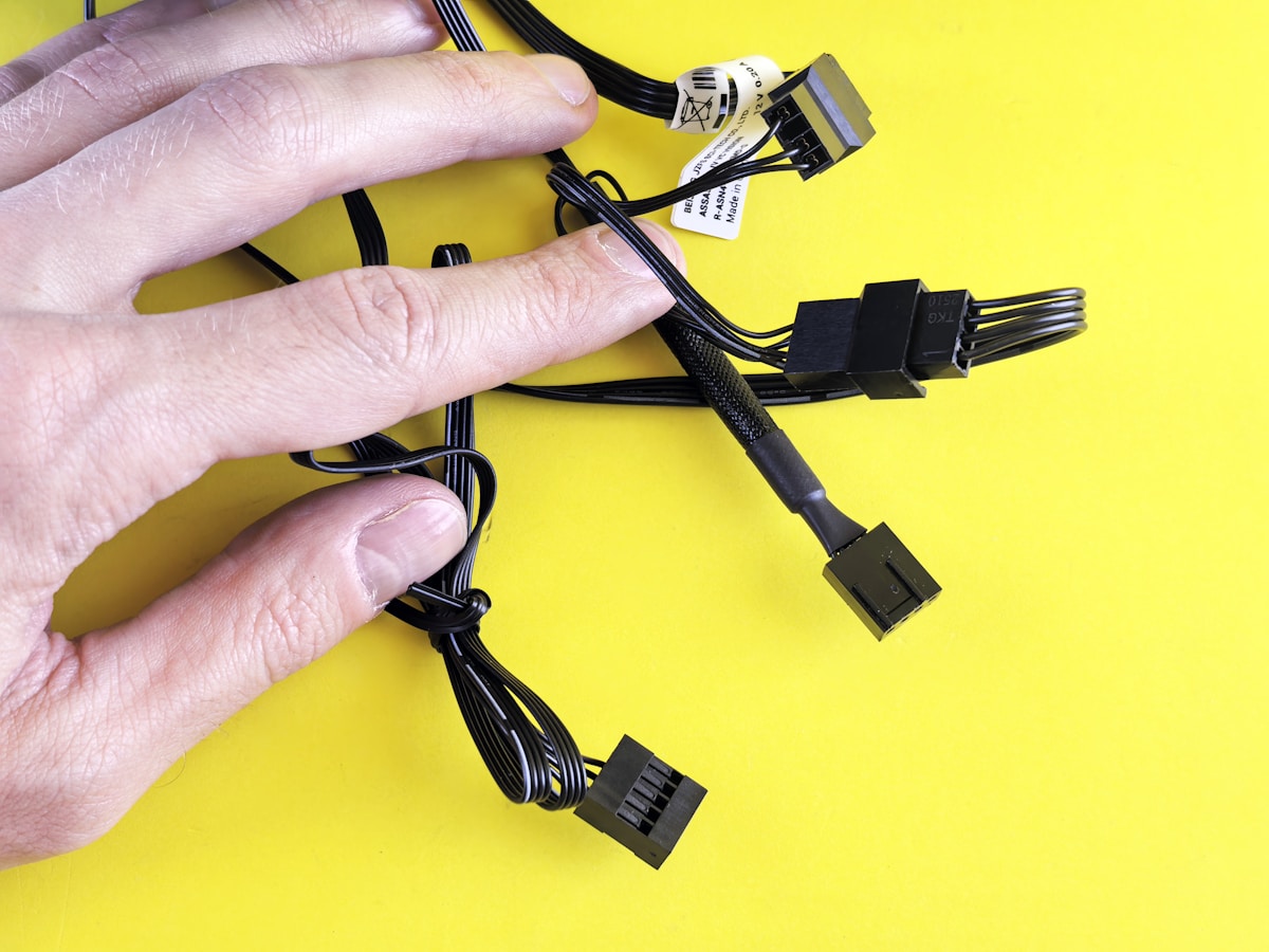 A hand touches computer cables on a yellow background