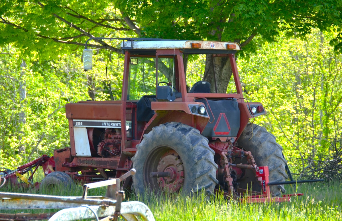 Old tractor sits on grassy land.