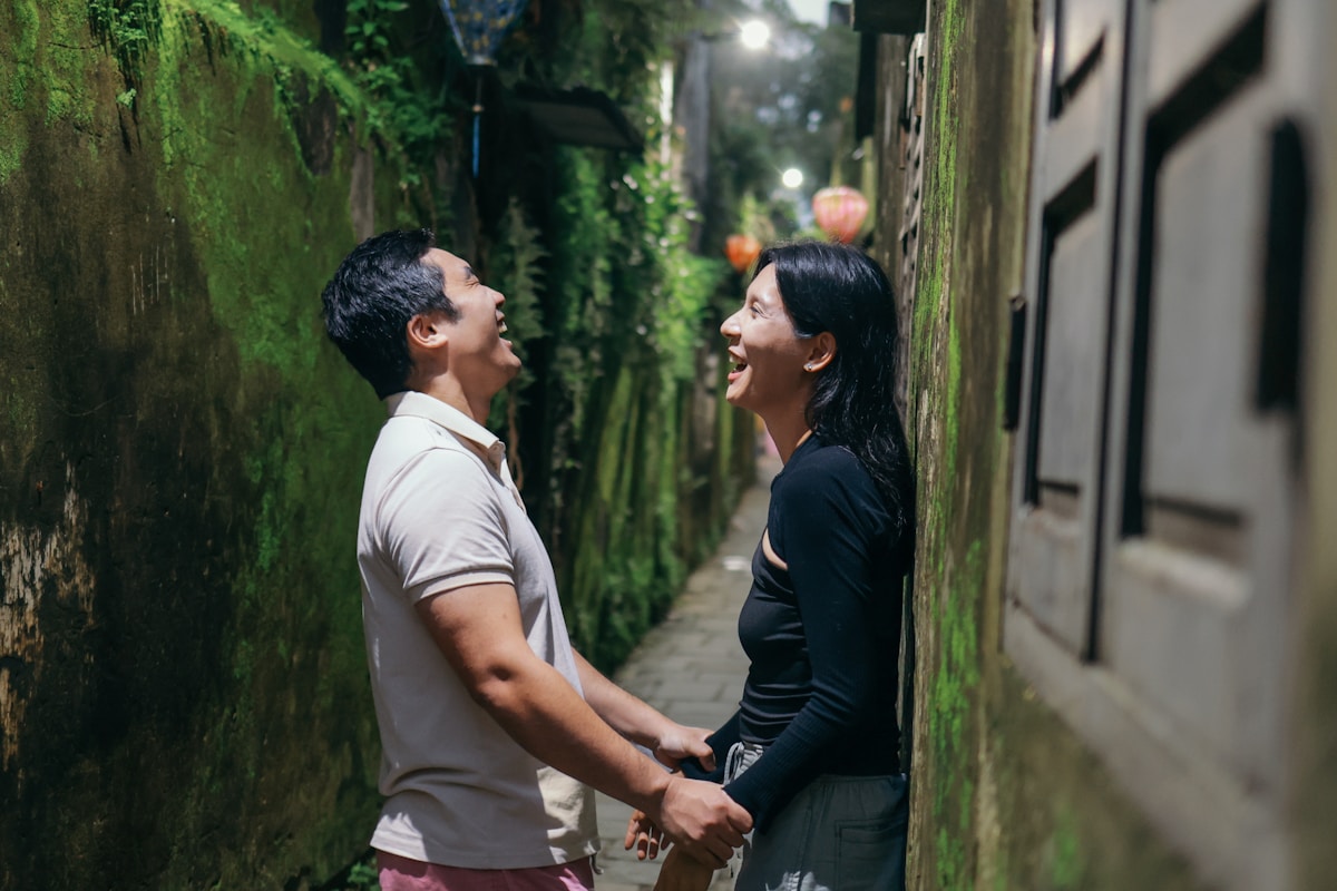 A couple laughing while holding hands in a narrow alley.