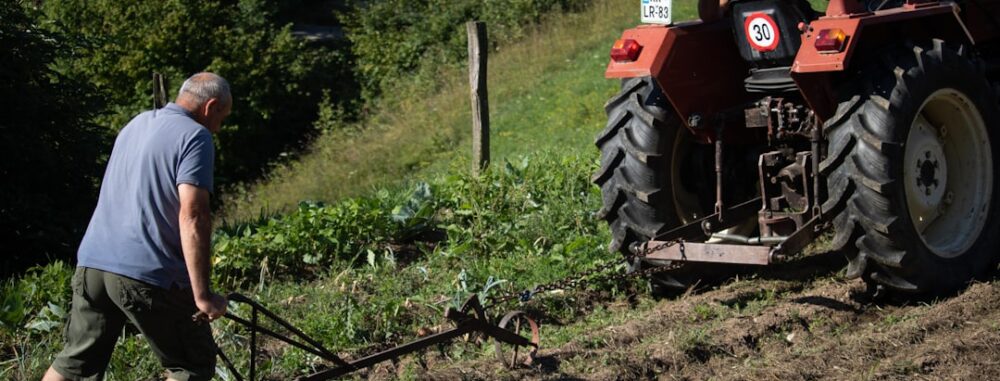 "Un agriculteur utilise un tracteur pour optimiser son désherbage mécanique en bio sur une pente herbeuse en labourant le cha