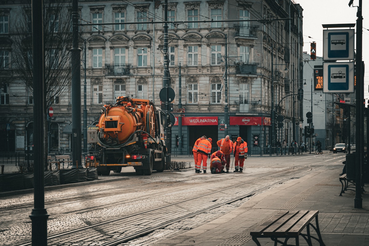 Workers in orange vests with a large orange truck.