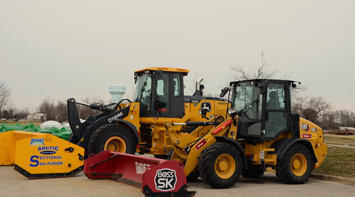 Équipement de construction jaune et vert, incluant un chargeur sur roues et un niveleuse.