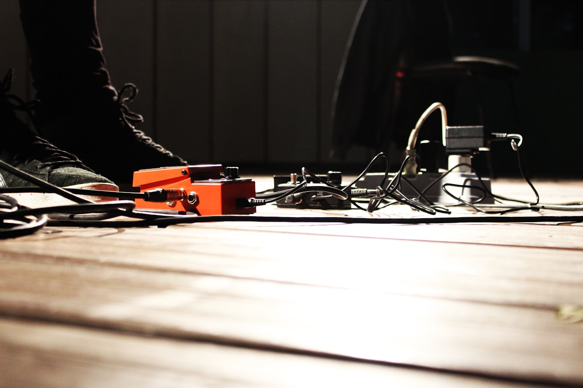 Outils électroniques et câbles éparpillés sur un sol en bois sombre.