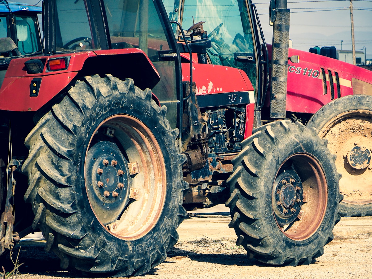 Tracteur agricole rouge avec de grandes roues de caoutchouc.