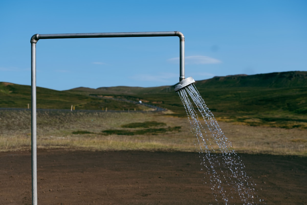 Douche extérieure dans un paysage de collines verdoyantes.