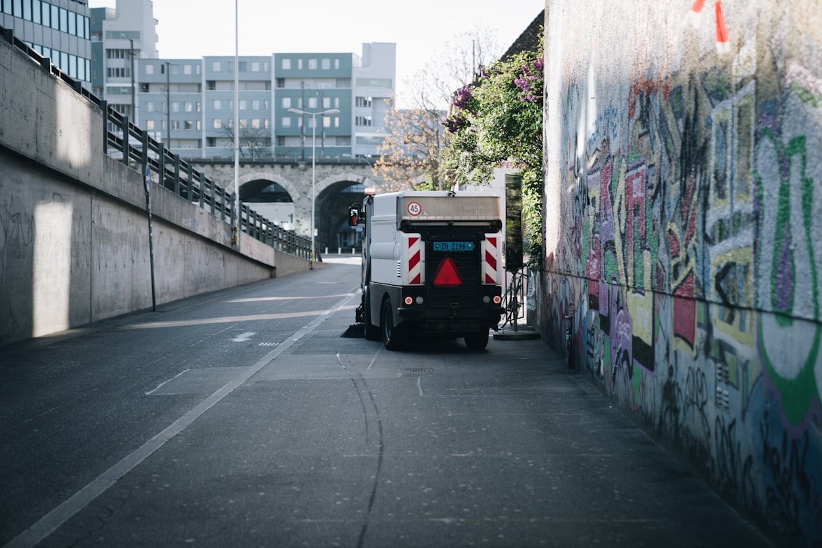 Rue urbaine avec graffitis, véhicule de service et architecture moderne.