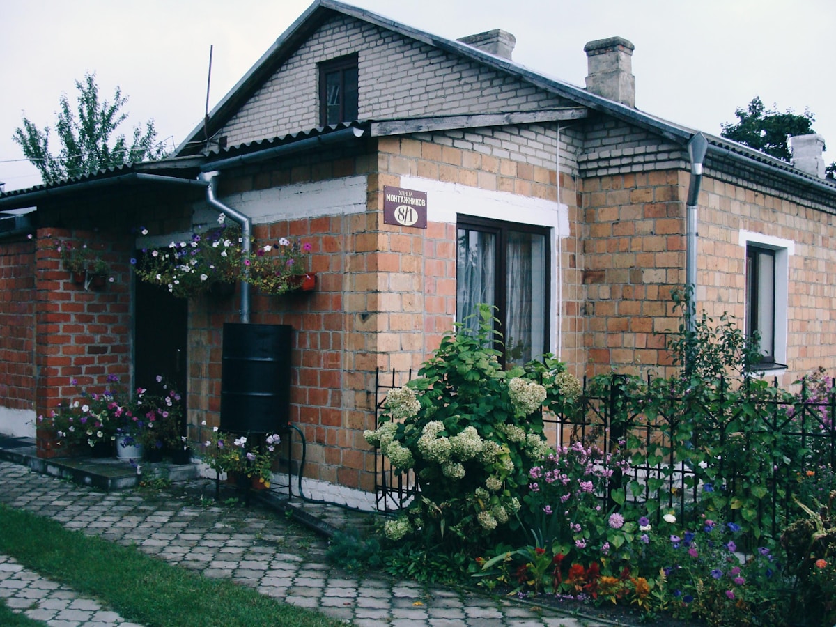 Maison de briques avec jardin fleuri et décorations extérieures.