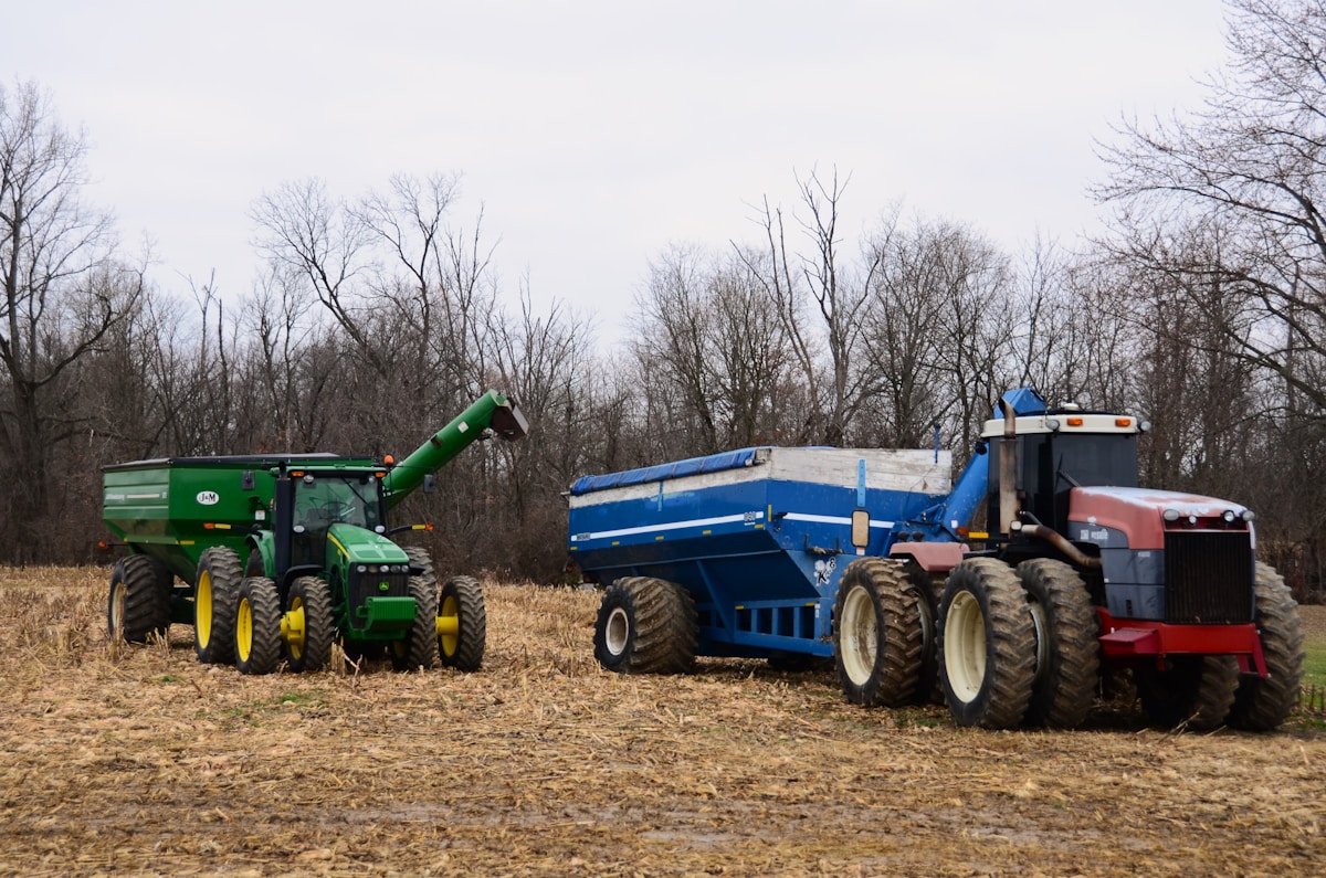 Tracteurs agricoles et remorque dans un champ en automne.