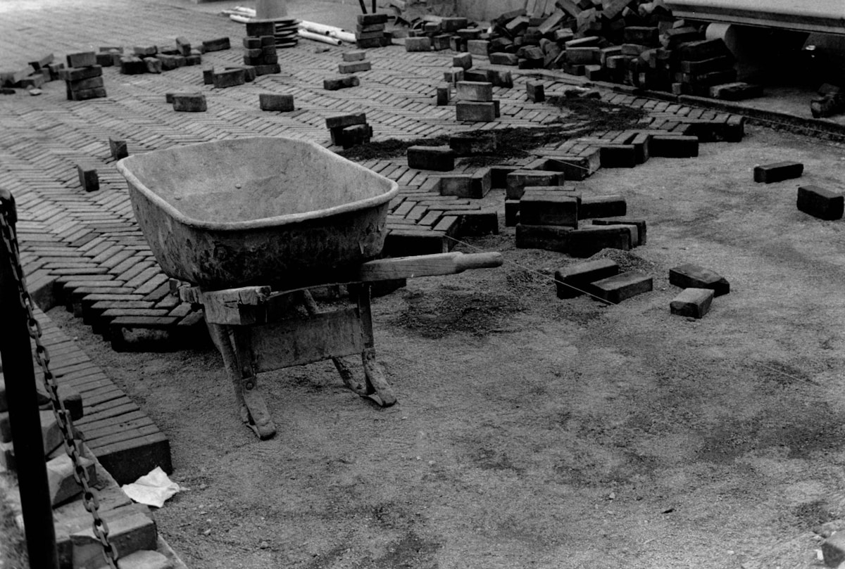 Brique, mortier, outils de construction éparpillés sur le sol.