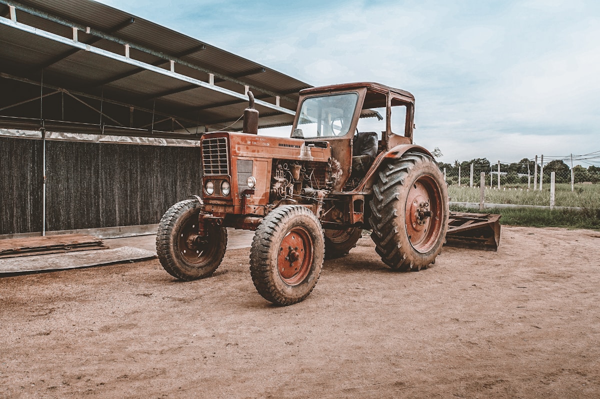 Tracteur agricole rouillé et vintage dans une grange.