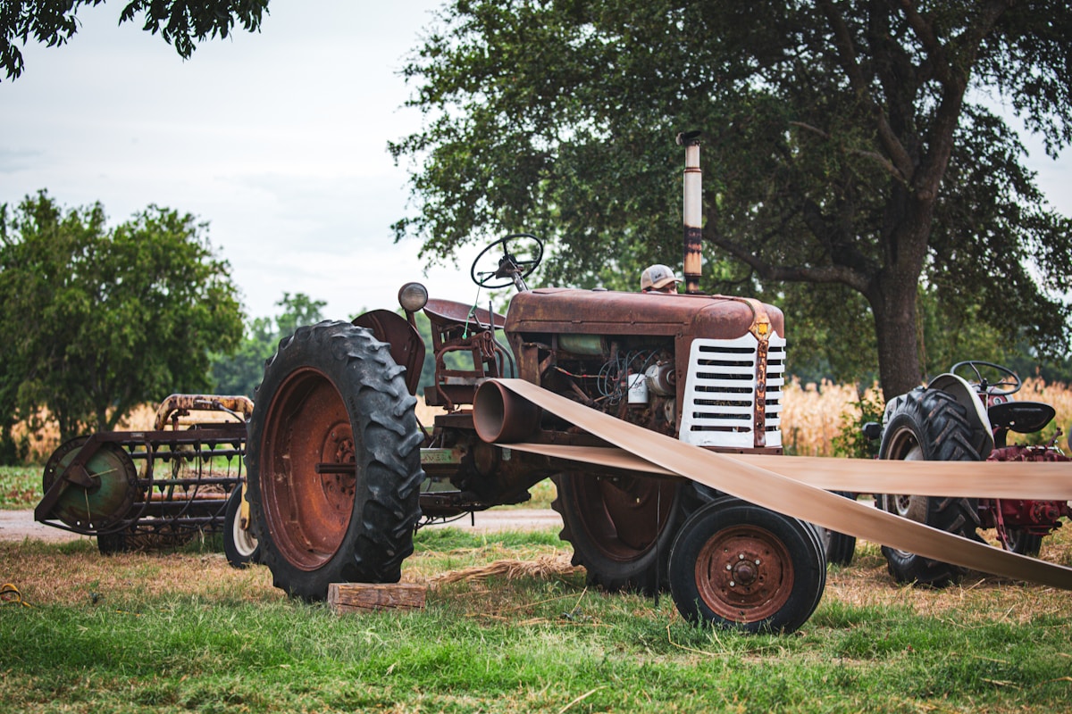 Tracteur agricole rouillé dans un champ verdoyant.