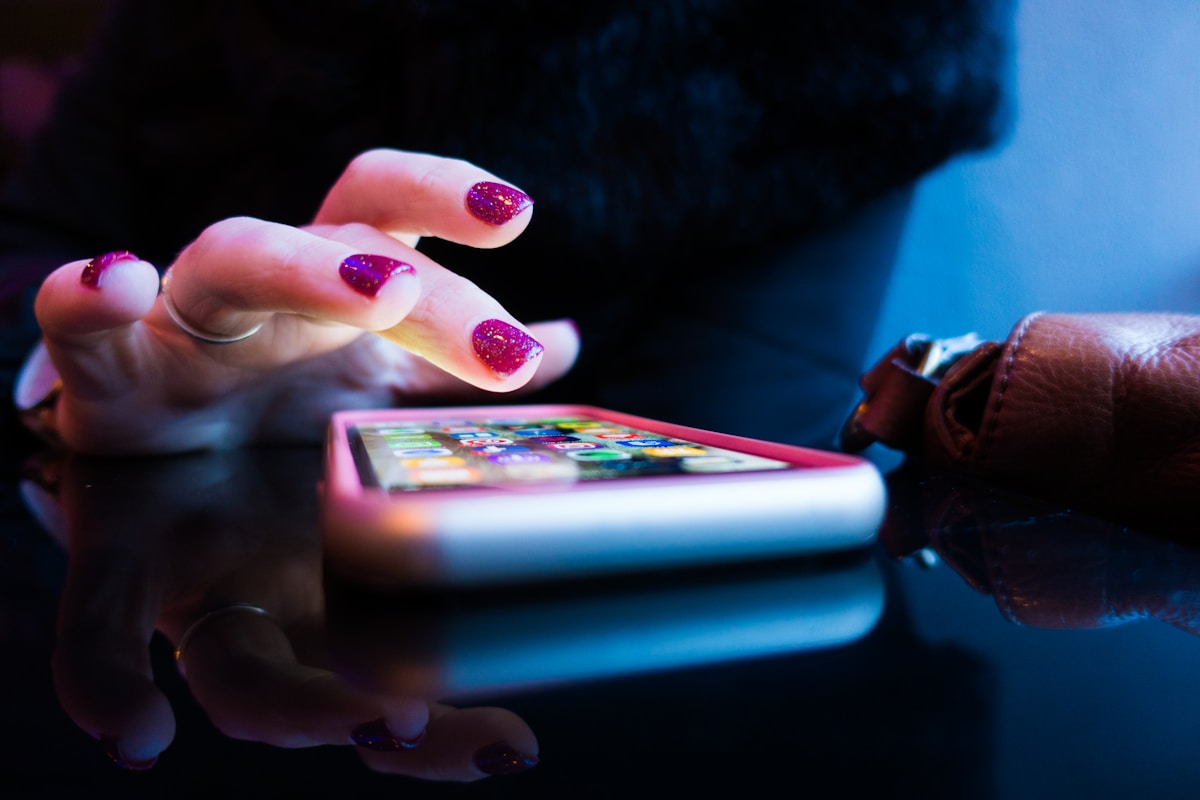 Mains féminines tenant un smartphone avec un écran lumineux.