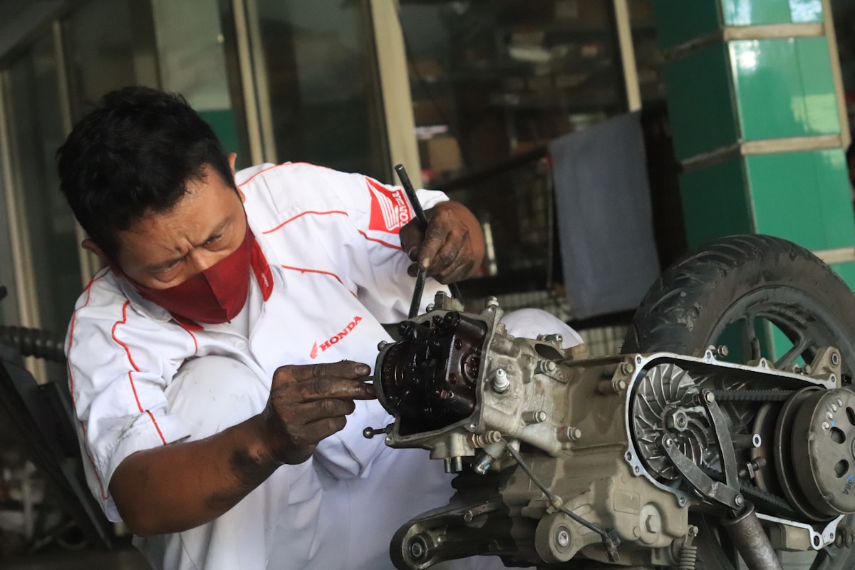 Mécanicien automobile réparant un moteur de moto Honda.