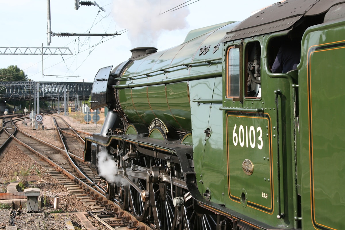 Locomotive à vapeur verte et noire sur les voies ferrées.